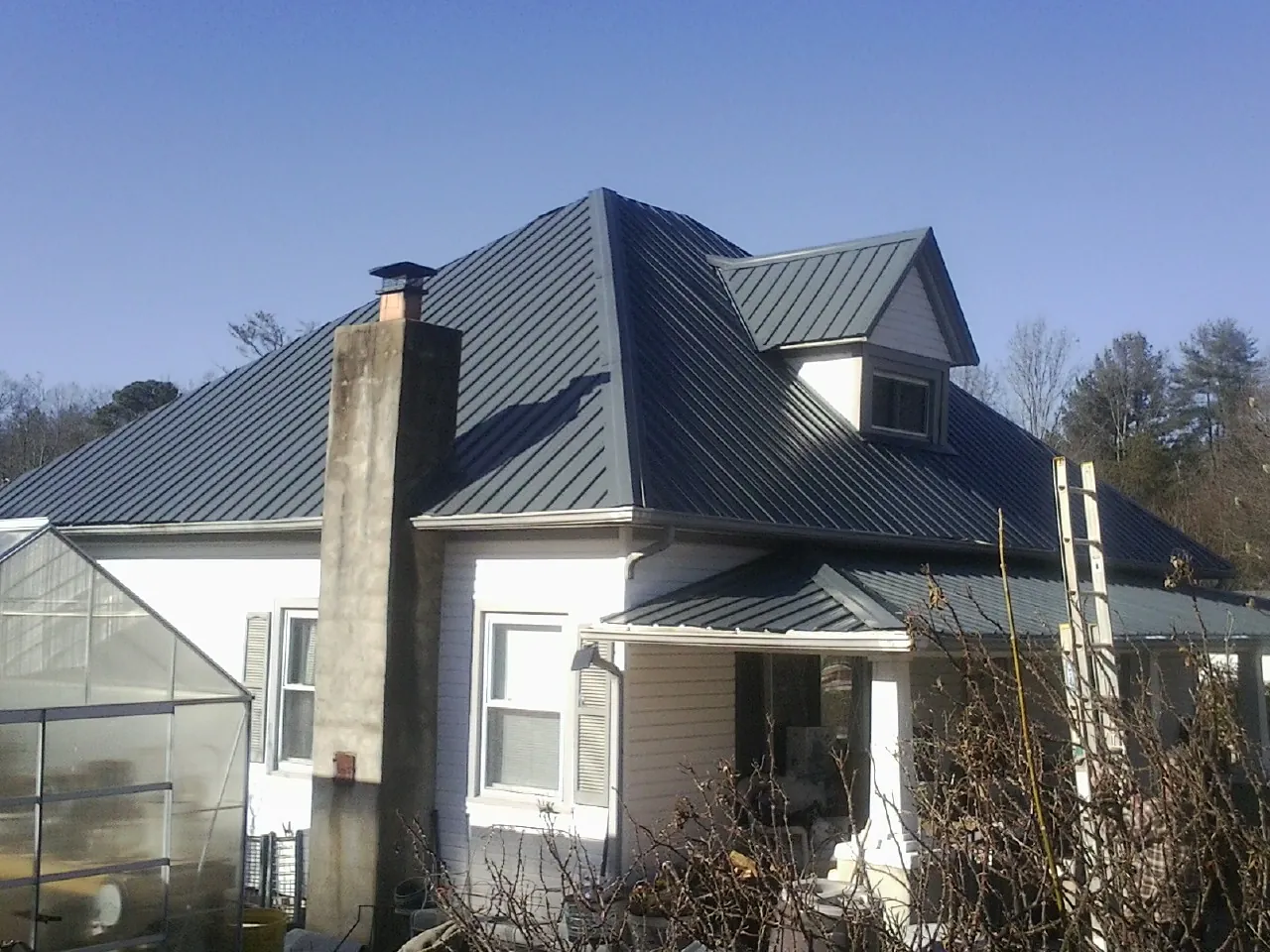 Dark blue standing seam metal roof on a white farmhouse with dormer — Slate & Tile Roof Repair by Roofing Brothers in Tupper Lake