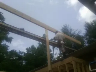 Carpenter setting a ridge beam over a new addition frame — Ice Dam Removal by Roofing Brothers in Tupper Lake