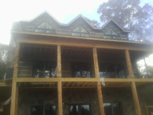 Dormers and porch framing on a large log home under construction — Roof Coating work by our crew in Tupper Lake