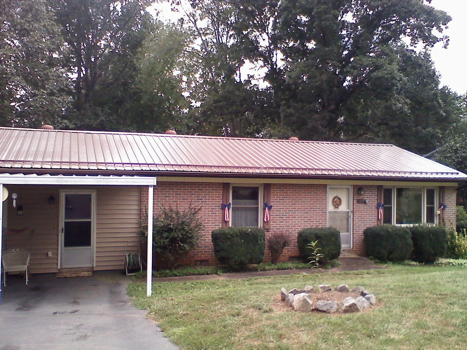 Bronze metal roof and carport on a brick ranch home — Roof Repair work by our crew in Tupper Lake